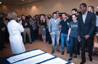 A crowd of students listens to a faculty in a white coat speaking during a Match Day event.